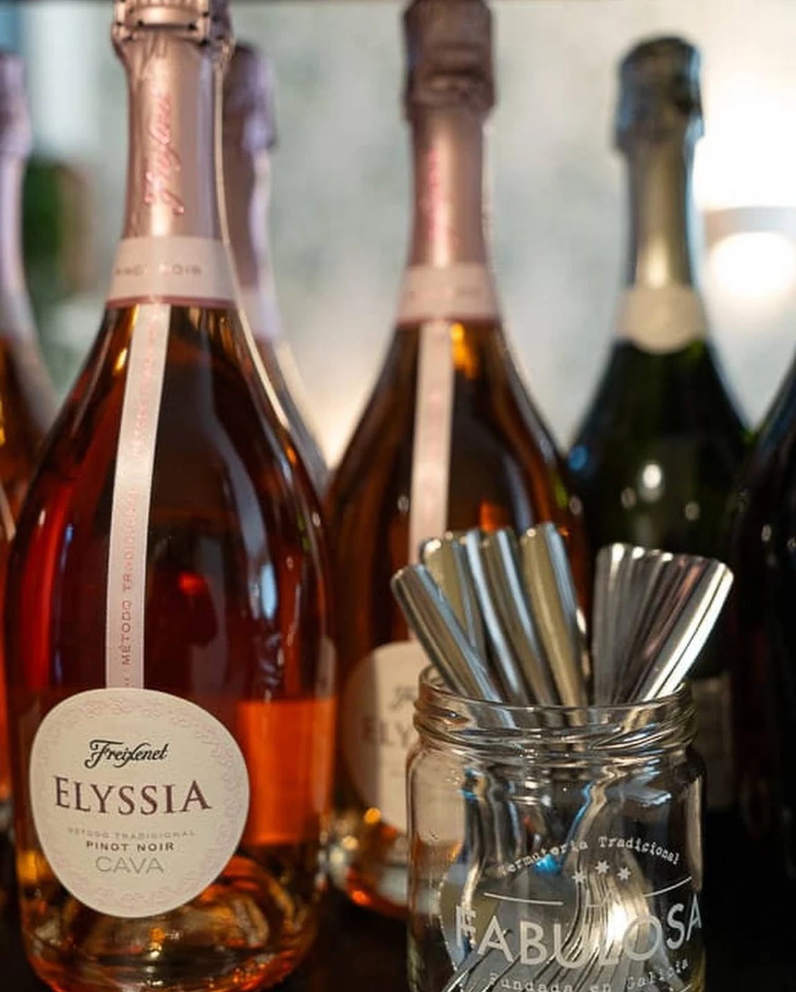 Botellas de cava Elyssia junto a las copas de la barra.