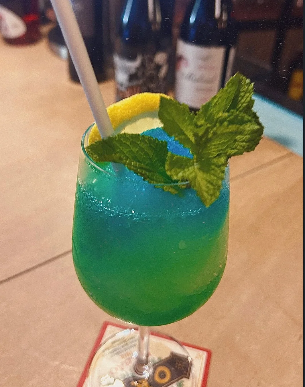Un cóctel azul y verde con hielo, hierbabuena y un toque de limón.