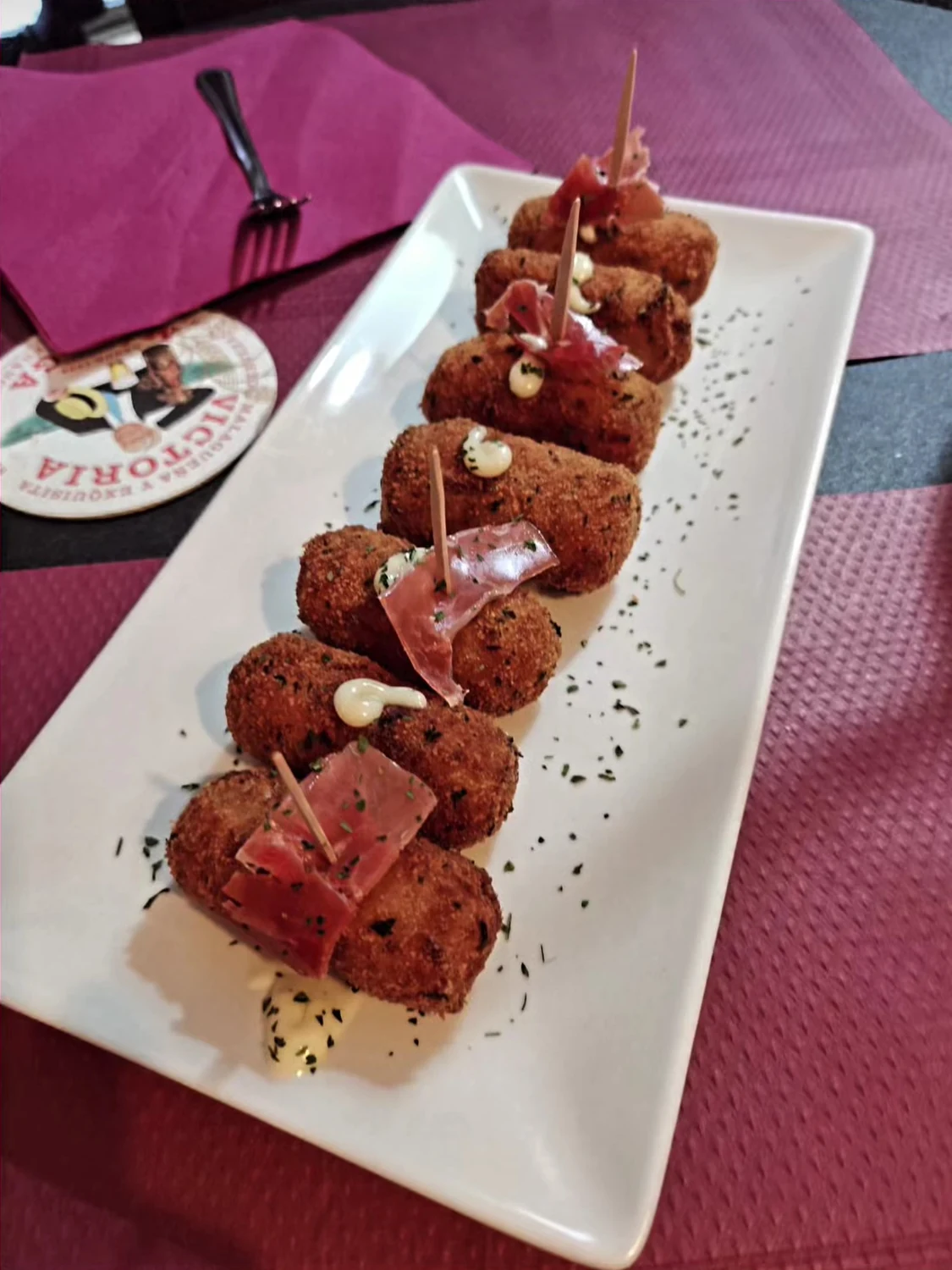 Croquetas doradas con jamón y pequeños toques de salsa.