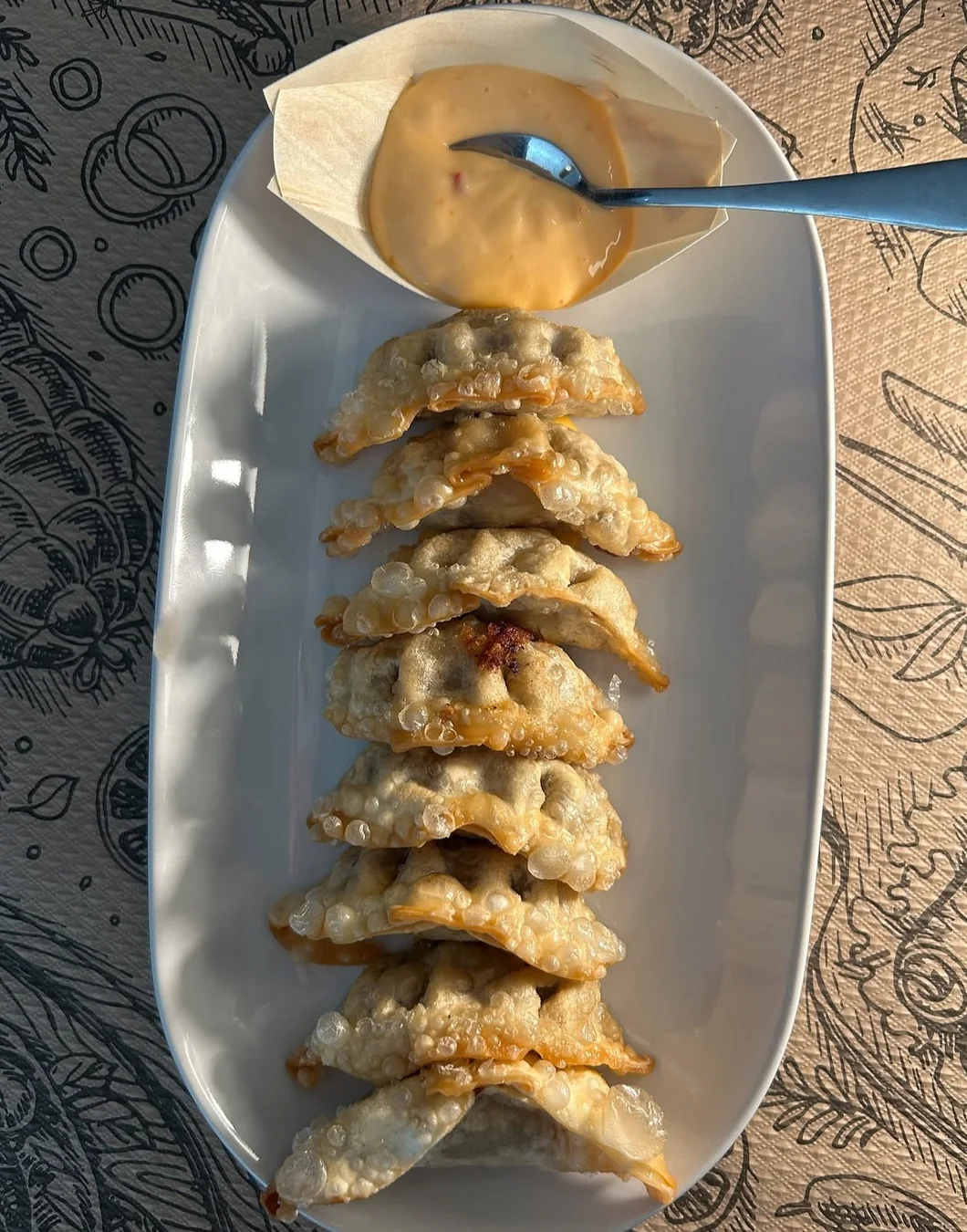 Un plato de gyozas acompañado de una salsa cremosa.