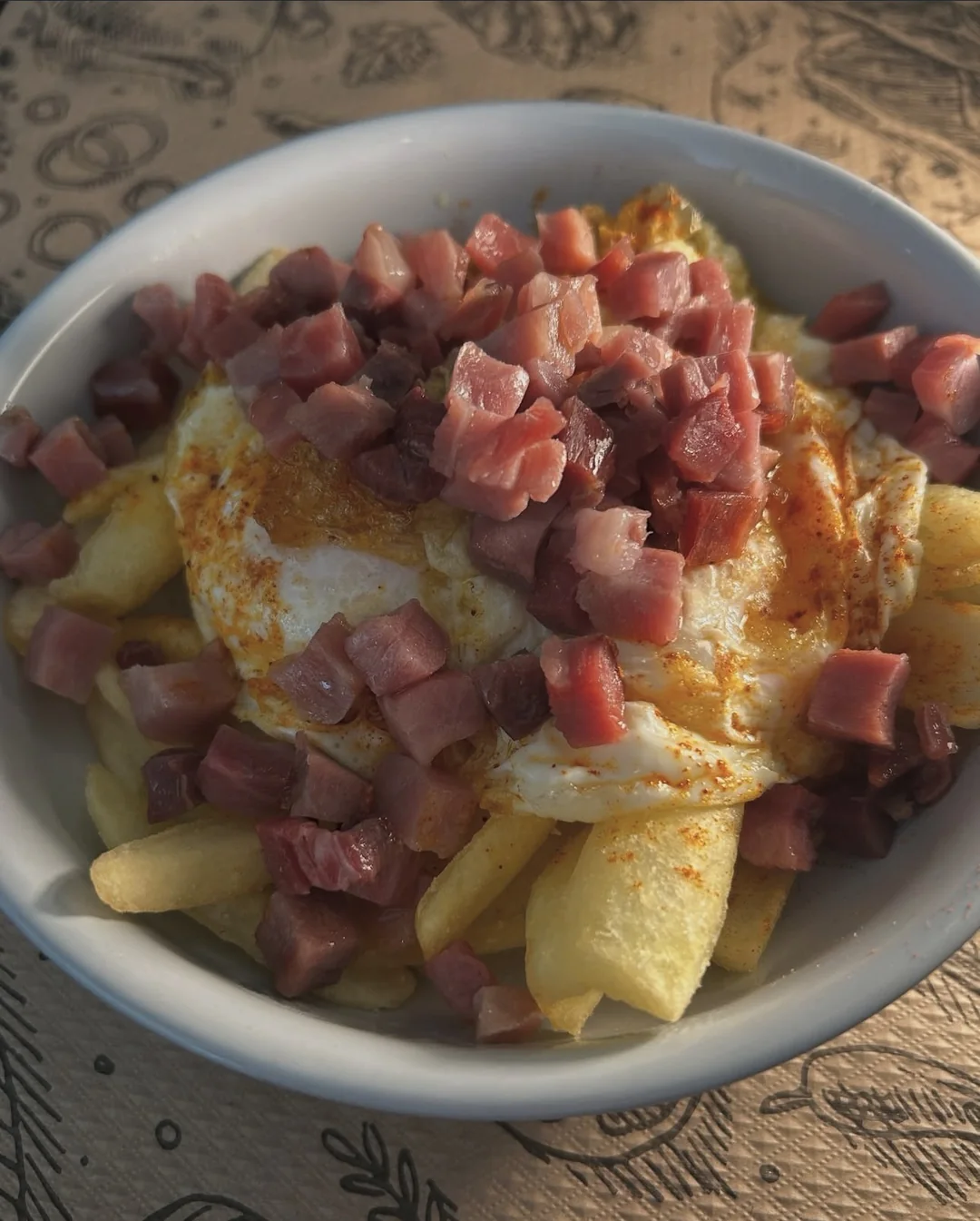 Un plato de huevos con patatas y tacos de jamón, pensado para compartir.