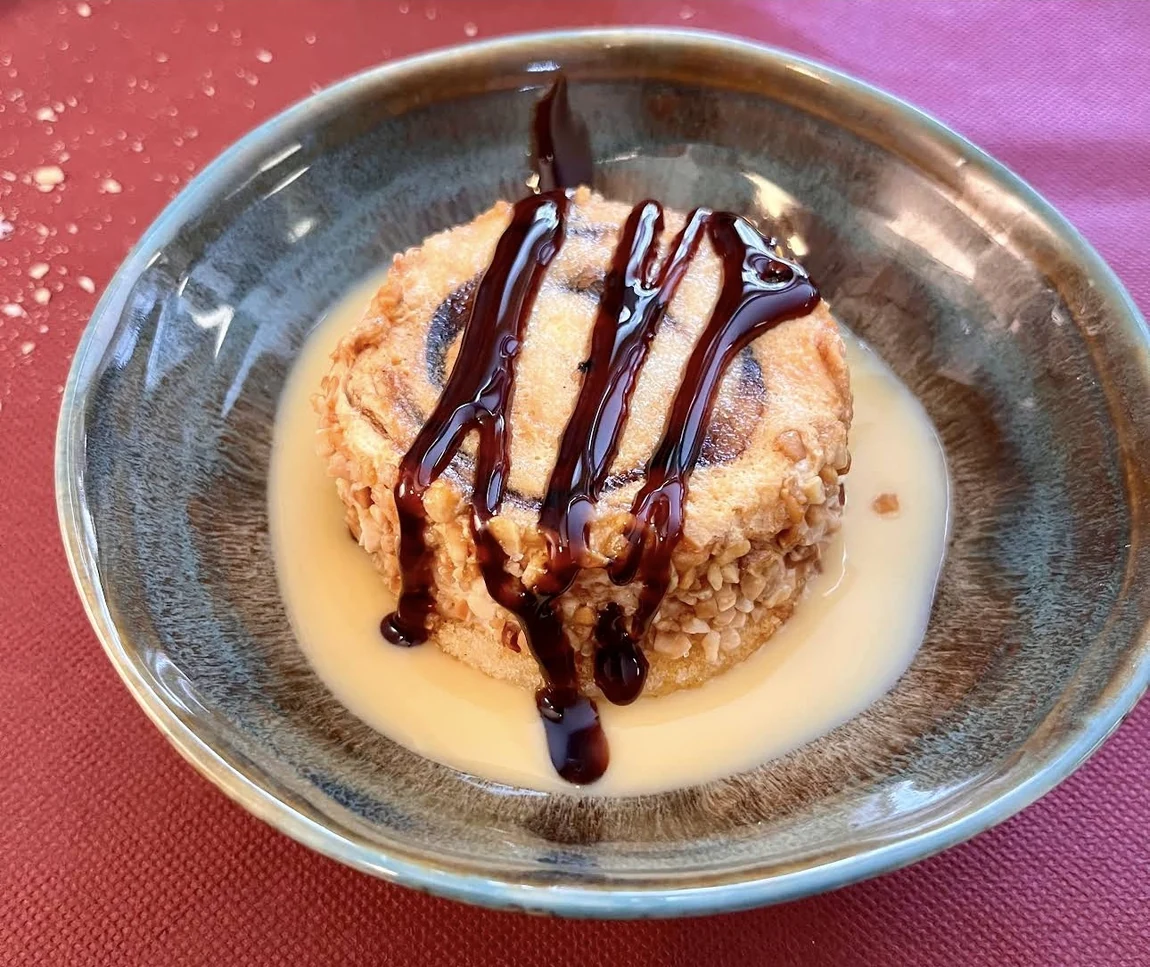 Un postre con crema y un toque de chocolate sobre un plato de cerámica.